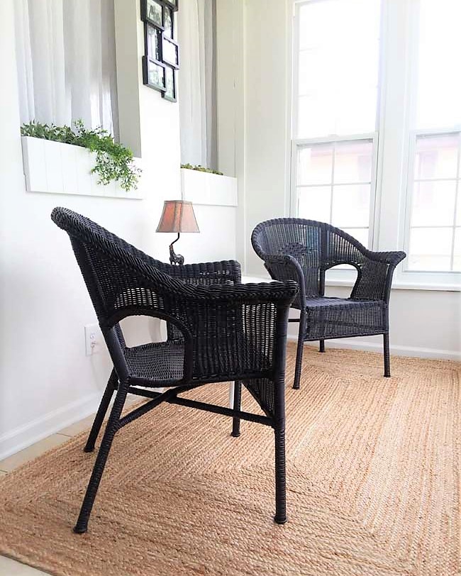 Black wicker chairs on small sun porch