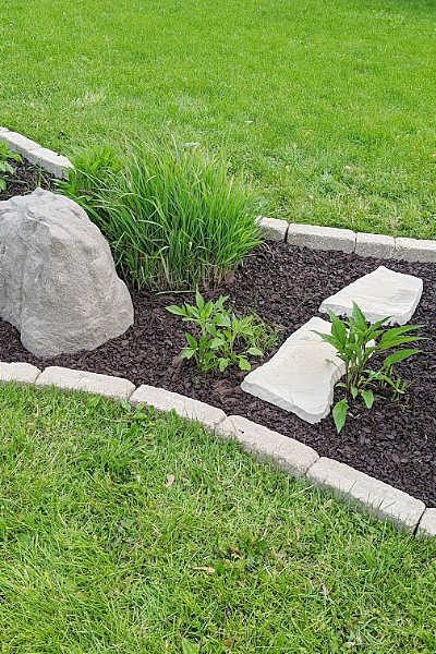 Garden bed with tumbled edgers, fake rock accents, brown rubber mulch