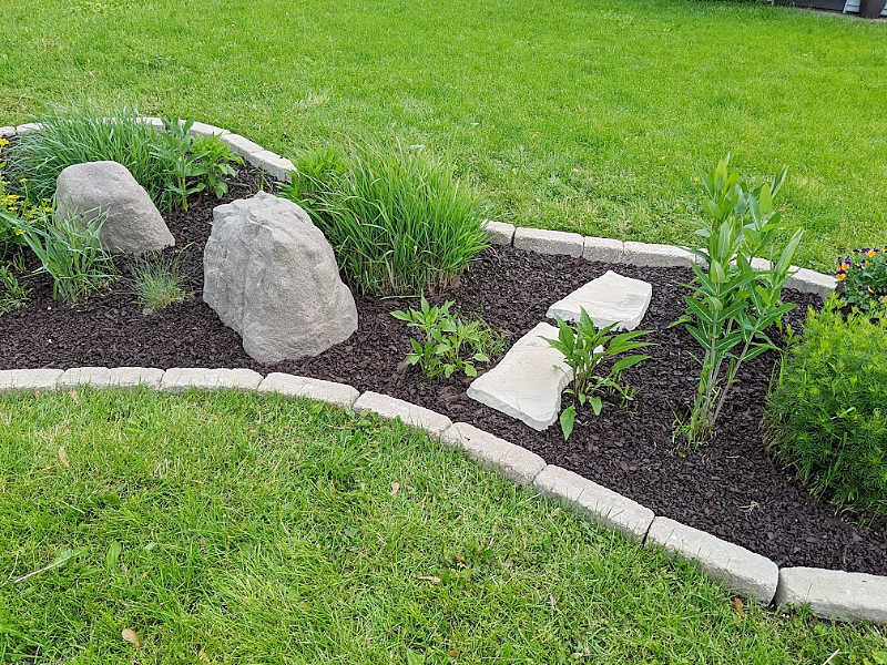 Garden bed with tumbled edgers, fake rock accents, brown rubber mulch