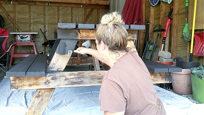 woman rolling solid stain on picnic table